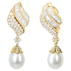 Delicate details indulge this spectacular pair of diamond South Sea pearl drop dangle earrings in splendid form. Crafted in fine 18k yellow gold, each earring features a lustrous 12.5-13.0mm South Sea cultured pearl set below an impressive array of 149 diamonds of 7.0 total cttw, that are of an approximate F-G color and VS1-VS2 clarity. The elegant teardrop-shaped pearl is of a light gray color with medium luster. The pearls are an art-form in a cup setting with scalloped design to form an encha Luxury Statement Pear-shaped Pearl Earrings, Luxury Chic Yellow Gold Pearl Earrings, Luxury Pearl Drop Chandbalis For Celebration, Pearl Centerpiece, Scalloped Design, Sea Pearl, Pearl Set, Pearl Types, South Sea Pearls