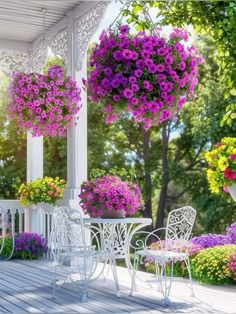 a white table and chairs sitting on top of a wooden deck next to flowers hanging from the ceiling