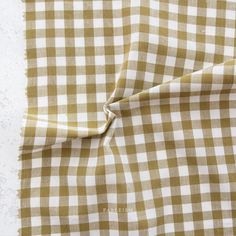 a checkered fabric is folded on top of a white tablecloth with a brown border