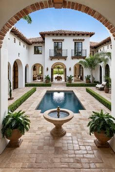 an outdoor courtyard with a fountain and potted plants in the foreground is shown