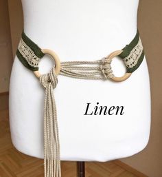 a white mannequin wearing a green and beige belt with two rings on it