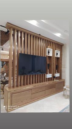 a living room with a large television and wooden paneling on the wall behind it