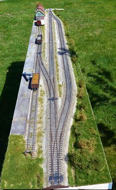 an overhead view of a train track with grass growing on the sides and tracks running parallel to each other