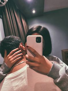 a woman taking a selfie with her cell phone in front of her face while sitting on a bed