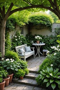 an outdoor patio with potted plants and white flowers on the ground, surrounded by greenery