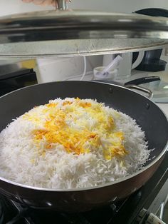 a pan filled with rice and cheese cooking on top of an open stove burner