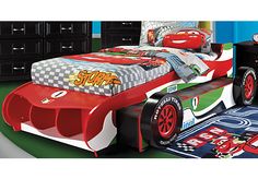 a child's bedroom with cars bedding and furniture