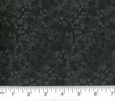 a ruler is next to a black and white floral pattern on a dark gray background