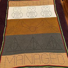 a crocheted blanket with the word mama written in large letters on it, sitting on a wooden floor