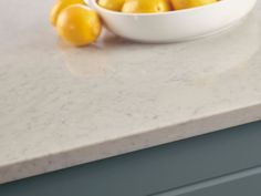 a white bowl filled with lemons on top of a counter