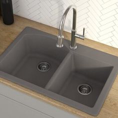 a kitchen sink with two faucets on the side and a wooden counter top