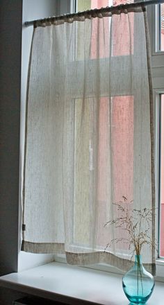 a vase with flowers in it sitting on a window sill next to a curtain