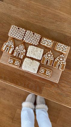 gingerbread cut out to look like houses and trees on a wooden table with someone standing next to it