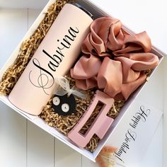 an open box containing a pink bottle, hair clip, and ribbon with the word fabulous written on it