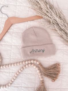 "Create a heartwarming, one-of-a-kind keepsake for your little one with our Personalized Newborn Beanie. This soft, cozy winter hat is expertly stitched with your baby's name, making it the perfect name announcement accessory. Crafted with warm and hypoallergenic 100% acrylic, this infant beanie is gentle on delicate skin while ensuring your baby stays comfy and toasty. Customize your baby's beanie hat by selecting one of our four stylish beanie colors and pairing it with one of 36 vibrant embroidery thread colors. Fine-tune your design with a choice of 5 fun fonts. This custom name hat is not just a snuggly winter essential but also a charming keepsake of your baby's early days. It makes a thoughtful, personalized baby gift for winter-born infants, perfect to gift on baby showers or baby' Personalized Cotton Birthday Hat, Winter Cotton Hat For Gifts, Cotton Winter Hat For Gift, Cotton Winter Hat As A Gift, Cotton Winter Hat As Gift, Winter Cotton Hat As Gift, One Size Fits Most Beanie Hats For Gifts, One Size Fits Most Beanie Gift, One Size Beanie Hats For Gifts