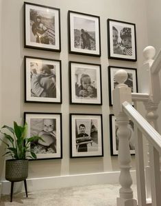 a bunch of black and white pictures hanging on the wall next to a stair case