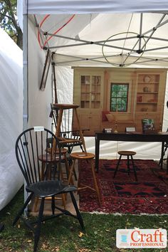 an outdoor tent with chairs and tables in the grass next to a table that is on top of a rug