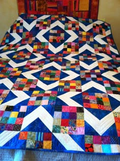 a bed with a colorful quilt on top of it