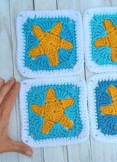 four crocheted squares with yellow and blue starfishs on them, sitting on a white wooden surface