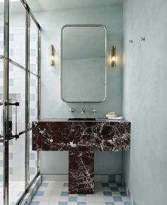 a bathroom with blue and white tile flooring, a marble sink and large mirror