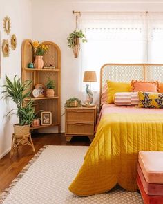 a bedroom with yellow and orange bedding, plants and decor on the shelves above