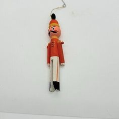 an orange and white wooden toy hanging from a hook on the side of a wall