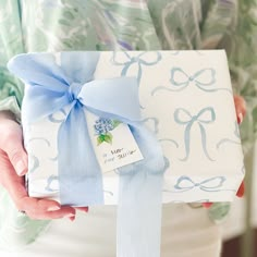 a woman holding a gift wrapped in blue ribbon