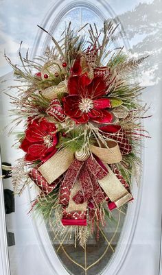 a red and gold christmas wreath hanging on the front door with burlap ribbon