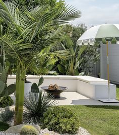 an umbrella is sitting on the side of a white wall next to plants and trees