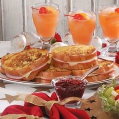 a table topped with lots of food next to glasses of orange juice and fruit on top of it