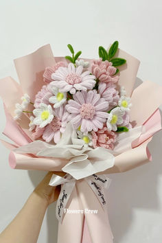 a bouquet of pink and white flowers is being held by someone's hand