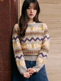 a woman standing next to a wall wearing a sweater