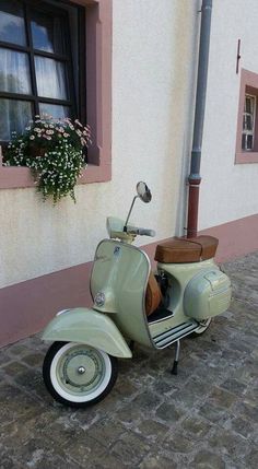 a moped parked in front of a building with a flower box on the back