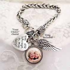 a silver bracelet with an angel charm and two charms on the clasps that says, you