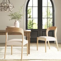 a dining room table with two chairs and a vase on the table next to it