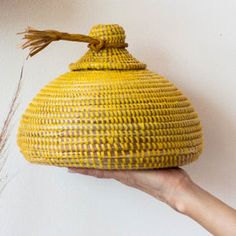 a hand holding a yellow woven basket