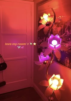 a pink room with flowers on the floor and lights in the corner, next to a door