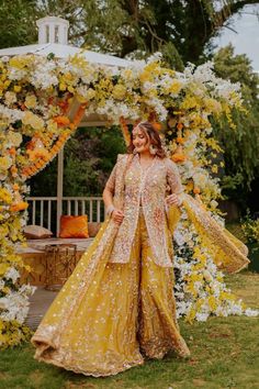 a woman standing in front of a floral arch