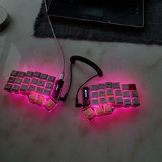 two glowing keyboards sitting on top of a table next to a laptop computer and mouse