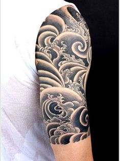 a man's arm with waves and clouds tattoo on his sleeve, in black and white