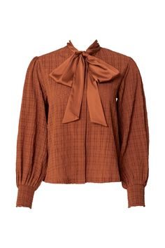 Introducing the Sybil Blouse in Brown! Made with durable brown woven fabric, this blouse features a high neckline with a functional bow for added style. The long balloon sleeve and smocked cuff add a touch of elegance, while the button up style makes it nursing friendly. The perfect addition to your wardrobe - versatile and chic! Just throw on your favorite pair of jeans and you have your new favorite fall outfit. Chic Smocked Top With Lantern Sleeves For Fall, Chic Lantern Sleeve Smocked Top For Fall, Long Sleeve Ruffled Smocked Top For Fall, Long Sleeve Smocked Top With Ruffles For Fall, Fall Balloon Sleeve Smocked Top With Smocked Cuffs, Fall Blouse With Pleated Bishop Sleeves, Chic Fall Blouse With Balloon Sleeves, Fall Puff Sleeve Smocked Top With Smocked Cuffs, Fall Smocked Puff Sleeve Top With Smocked Cuffs