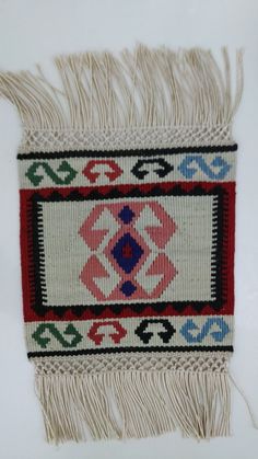 a piece of cloth with fringes and designs on the front, sitting on a white surface