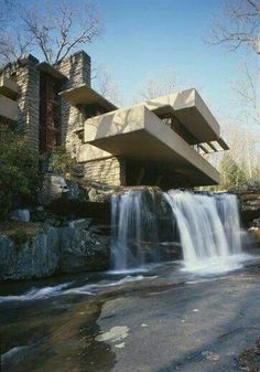 a black and white photo of a waterfall in front of a building with a large window