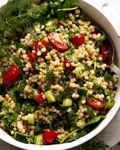 a white bowl filled with couscouse and vegetables on top of a table