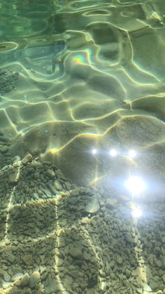 the sun shines brightly through clear water on rocks and pebbles in shallow, crystal waters