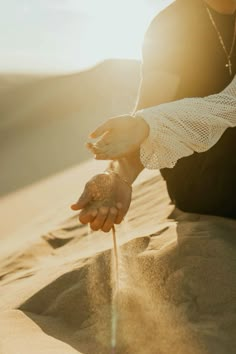 a person kneeling down in the sand with their hand reaching out to touch some sand