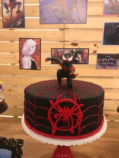 there is a spiderman cake on top of a table with other decorations and pictures behind it