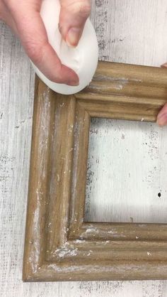 two hands are working on an old wooden frame with glue and wood shavings