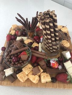 an assortment of chocolates, strawberries and crackers on a wooden platter