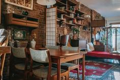 a dining room table and chairs in front of a brick wall